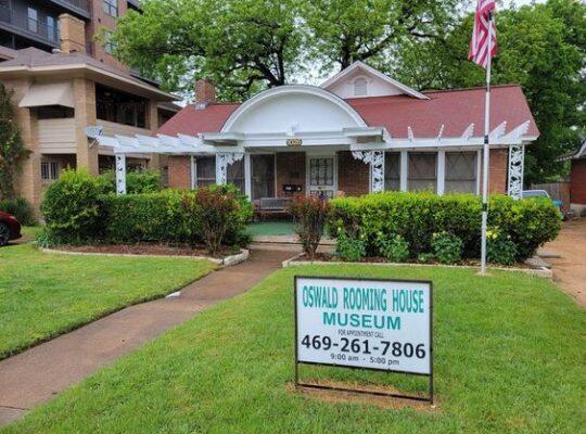 Garden view of the Oswald Rooming House Museum in Dallas, Texas, showcasing historic architecture and green landscaping surrounding the property.