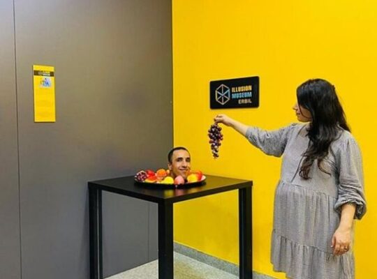 Woman participating in an interactive illusion exhibit at the Museum of Illusions, Dallas, appearing to defy gravity in a mind-bending activity.