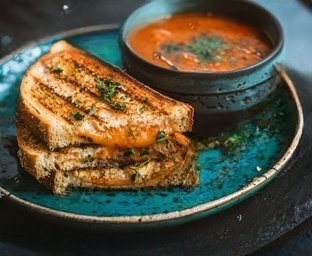 Melted grilled cheese sandwiches from a Dallas food truck, featuring crispy golden bread and gooey cheese, served with a side of dipping sauce.