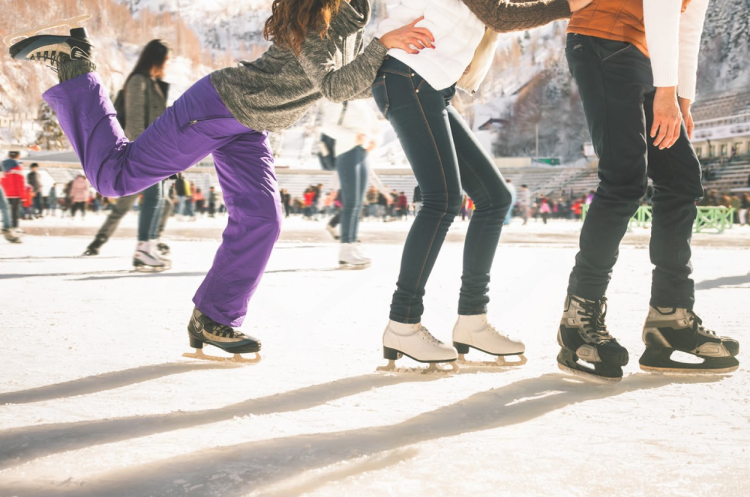 "Three friends enjoy ice skating together outdoors, surrounded by a lively crowd and snow-covered scenery." one of the activity from the Dallas winter bucket.