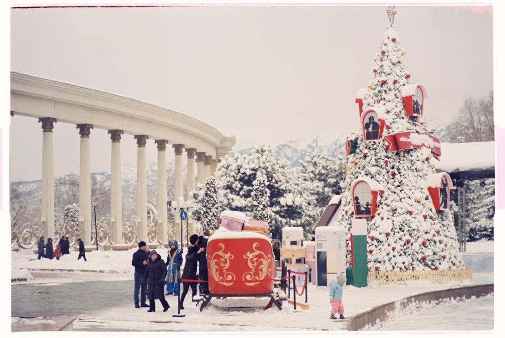 "A snow-covered town square features a grand Christmas tree adorned with festive decorations, a red sleigh display, and a majestic colonnade in the background." one of the activity from the Dallas winter bucket.